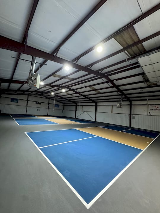 Indoor pickleball court blue gold commercial facility barn